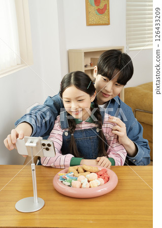 A cute child YouTuber who sets up his smartphone and films a mukbang with his dad. 126433209