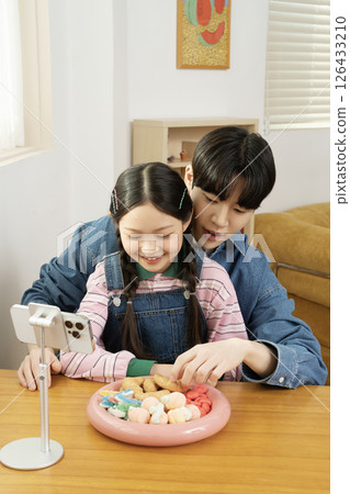 A cute child YouTuber who sets up his smartphone and films a mukbang with his dad. A cute child YouTuber who sets up his smartphone and films a mukbang with his dad. 126433210