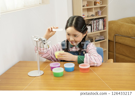 A cute child YouTuber who puts his smartphone upright and takes pictures while playing with slime. 126433217