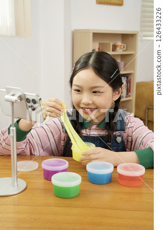 A cute child YouTuber who puts his smartphone upright and takes pictures while playing with slime. 126433226