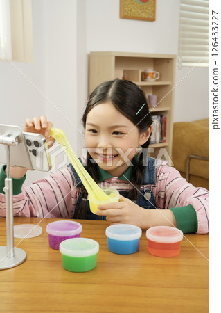 A cute child YouTuber who puts his smartphone upright and takes pictures while playing with slime. 126433227