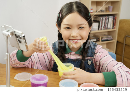 A cute child YouTuber who puts his smartphone upright and takes pictures while playing with slime. 126433229