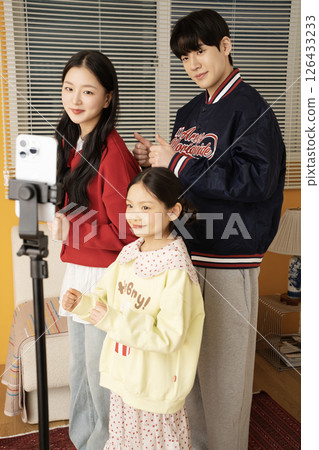 The MZ family filming a short-form challenge with a mobile phone tripod set up. 126433233