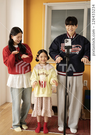 The MZ family filming a short-form challenge with a mobile phone tripod set up. The MZ family filming a short-form challenge with a mobile phone tripod set up. 126433234