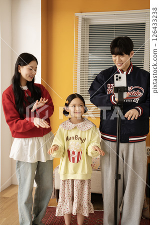 The MZ family filming a short-form challenge with a mobile phone tripod set up. 126433238