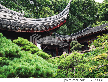 Traditional architecture blends harmoniously with lush greenery in an ancient garden setting. Traditional architecture blends harmoniously with lush greenery in an ancient garden setting. 126433315