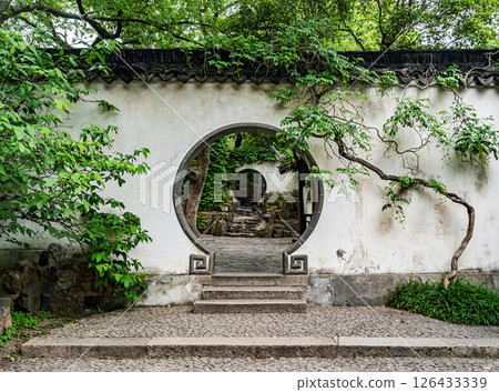 Garden entrance with circular arch and lush greenery in peaceful surroundings Garden entrance with circular arch and lush greenery in peaceful surroundings 126433339