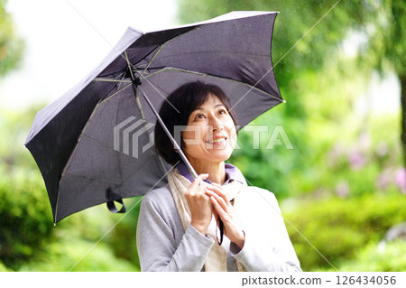 雨中撐傘站著微笑的中年婦女 126434056