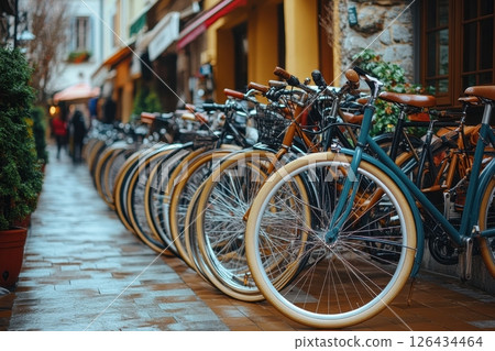 Rows of vintage bicycles with cream-colored tires are parked along a charming cobblestone street 126434464
