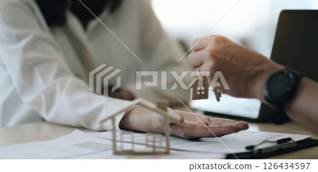 real estate agent holding house key to his client after signing contract agreement in office,concept for real estate, moving home or renting property real estate agent holding house key to his client after signing contract agreement in office,concept for real estate, moving home or renting property 126434597
