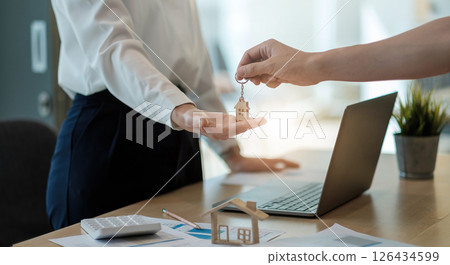 real estate agent holding house key to his client after signing contract agreement in office,concept for real estate, moving home or renting property real estate agent holding house key to his client after signing contract agreement in office,concept for real estate, moving home or renting property 126434599