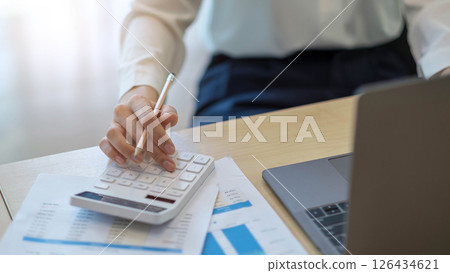 woman calculating individual income tax from financial document during note some data to sticky on window glass with calculator. 126434621
