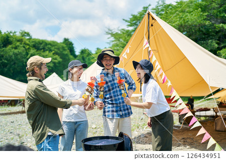 Men and women enjoying a barbecue at a campsite Men and women enjoying a barbecue at a campsite 126434951