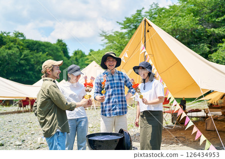 Men and women enjoying a barbecue at a campsite Men and women enjoying a barbecue at a campsite 126434953