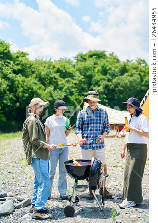 Men and women enjoying a barbecue at a campsite 126434955