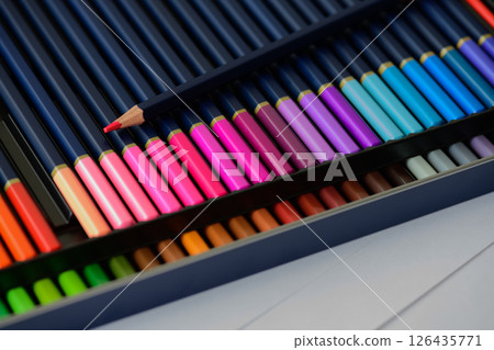 Two rows of colored pencils with a sharp point on red pencil in pencil case Two rows of colored pencils with a sharp point on red pencil in pencil case 126435771
