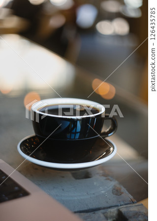 Delicious Black Coffee on a Table Surrounded by a Warm, Cozy Cafe Ambiance and Atmosphere 126435785