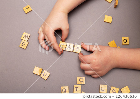 child hand hands collecting word cat from wooden cubes on gray background. child hand hands collecting word cat from wooden cubes on gray background. 126436630