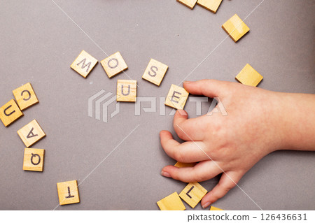 child hand hands collecting word mouse from wooden cubes on gray background. child hand hands collecting word mouse from wooden cubes on gray background. 126436631