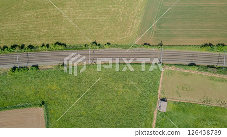 Stunning aerial view of railway tracks through lush green fields, showcasing natures beauty Stunning aerial view of railway tracks through lush green fields, showcasing natures beauty 126438789