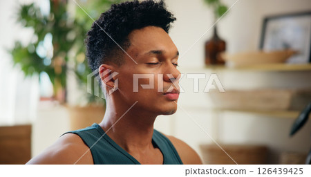 Man, calm and breathing for yoga at house for meditation, zen balance and mindfulness in lounge. Male person, eyes closed and chakra practice of morning peace, spiritual healing and holistic wellness Man, calm and breathing for yoga at house for meditation, zen balance and mindfulness in lounge. Male person, eyes closed and chakra practice of morning peace, spiritual healing and holistic wellness 126439425