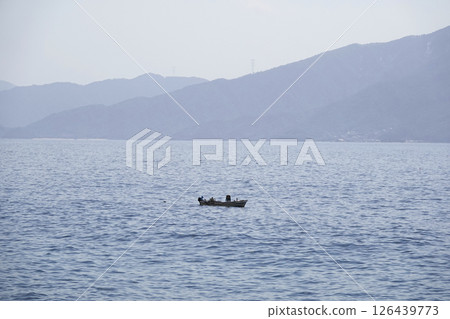 春日里,平靜的海面上,一位漁夫正在捕魚 春日里,平靜的海面上,一位漁夫正在捕魚 126439773