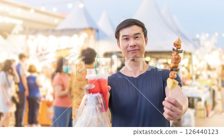 An Asian young man travels with street food. 126440123