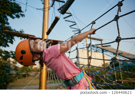 School girl climbing in adventure rope city park on summer day 126440621