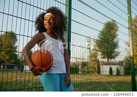 Portrait of attractive female basketball player with ball at sport ground Portrait of attractive female basketball player with ball at sport ground 126440651
