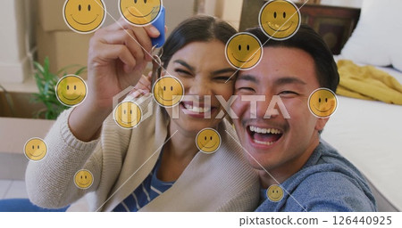 Image of smiley face icons over happy biracial couple with house key 126440925