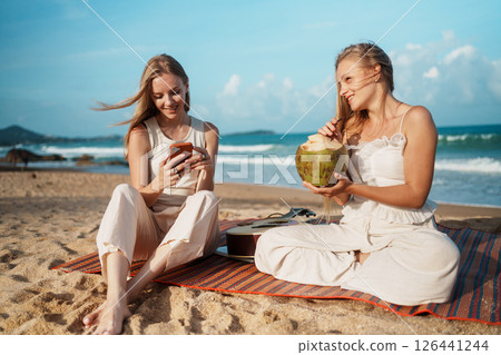 Young Women Having Fun on the Beach with Drinks and Smartphones 126441244