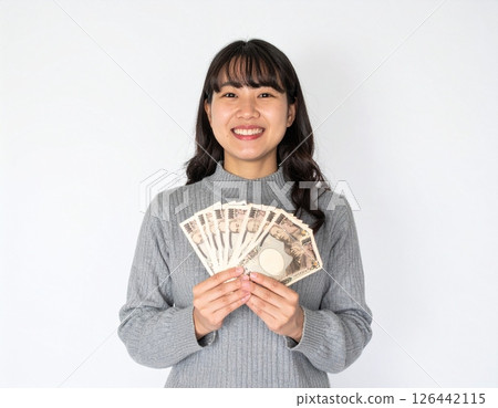Smiling young woman holding money 126442115