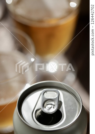 空罐子,將部分啤酒倒入啤酒杯中 空罐子,將部分啤酒倒入啤酒杯中 126442702