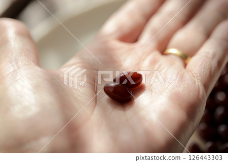 The hand of a woman in her 50s holding two placenta supplement tablets The hand of a woman in her 50s holding two placenta supplement tablets 126443303