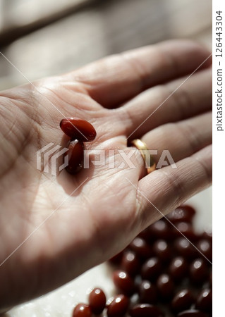 The hand of a woman in her 50s holding two placenta supplement tablets 126443304
