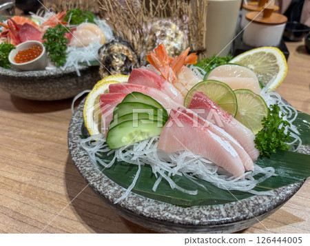 Fresh sashimi platter with assorted fish and garnishes served on a wooden table at a Japanese restaurant 126444005