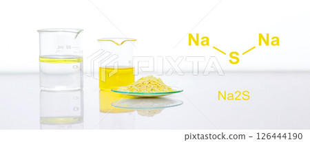 Sodium sulfide flake in Chemical Watch Glass place next to beaker on white laboratory table. The structure of a chemical compound is shown on the side. 126444190