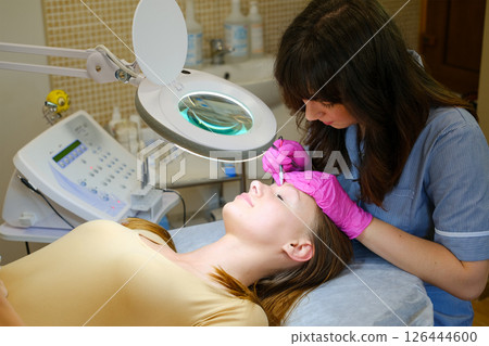 Young beautiful female dermatologist doing hair removal treatment on patient's face with electrolysis. Epilation and beauty concept. High quality photo Young beautiful female dermatologist doing hair removal treatment on patient's face with electrolysis. Epilation and beauty concept. High quality photo 126444600