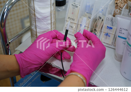 Woman - electrolysis specialist is setting up for hair removal procedure. Epilation and beauty concept.. High quality photo 126444612