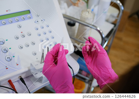 Woman - electrolysis specialist is setting up hair removal machine. Epilation and beauty concept.. High quality photo 126444626