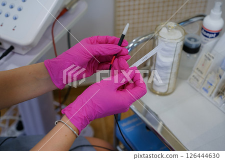 Woman - electrolysis specialist is setting up for hair removal procedure. Epilation and beauty concept.. High quality photo Woman - electrolysis specialist is setting up for hair removal procedure. Epilation and beauty concept.. High quality photo 126444630