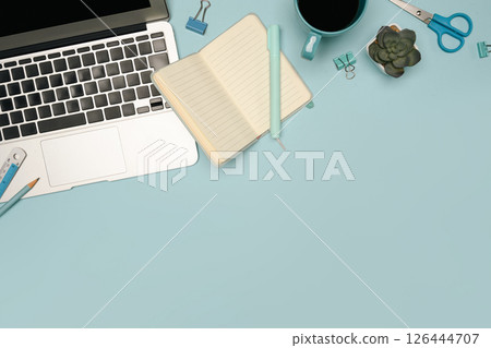 Flat lay of creative desk setup with office supplies and laptop on pastel blue background Flat lay of creative desk setup with office supplies and laptop on pastel blue background 126444707