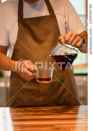 Cropped shot of man pouring fresh brewed coffee into glass cup in a kitchen 126444736