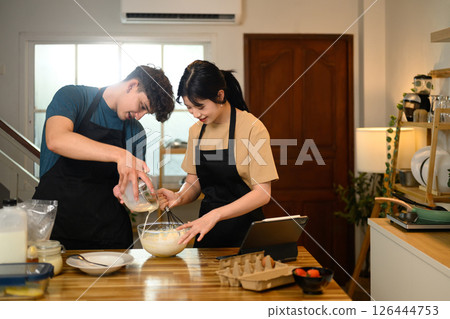 Smiling couple preparing pancake batter together in the kitchen Smiling couple preparing pancake batter together in the kitchen 126444753