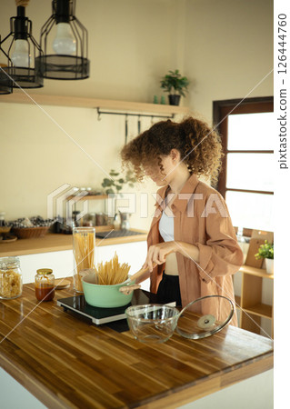 Young woman in casual clothes preparing a meal in a cozy kitchen 126444760