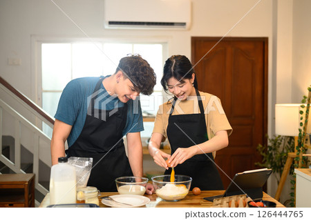 Smiling couple preparing pancake batter together in the kitchen 126444765