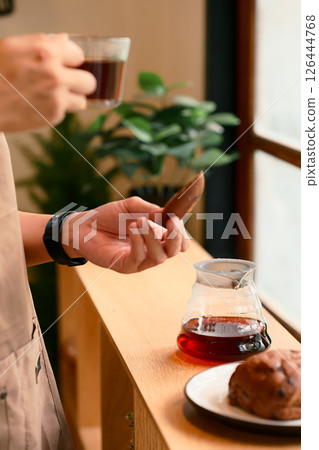 Close up of man brewing coffee with pour over method using a glass dripper in a kitchen Close up of man brewing coffee with pour over method using a glass dripper in a kitchen 126444768