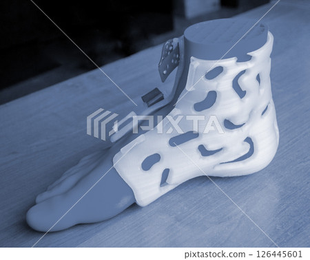 Prosthesis printed on a 3D printer from molten plastic on a plastic foot. Prototype of medical prosthesis for foot created on 3D printer. Medical orthosis, fixator, splint corset langet from plastic 126445601