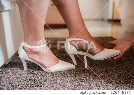 Bride Putting on Wedding Shoes with Assistance Bride Putting on Wedding Shoes with Assistance 126446175