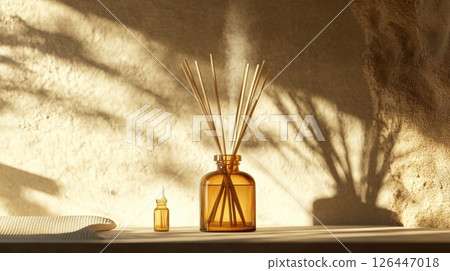 Elegant aromatic diffuser with amber glass bottle and wooden sticks casting gentle shadows in warm sunlit room with relaxing atmosphere. Spa accessory composition set in spa hotel 126447018